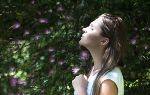 Woman breathing against background of flowers and leaves