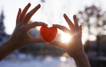 Woman holding heart-shaped snowball, close-up of hands