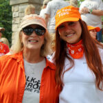 Two women wearing baseball hats smile towards the camera.