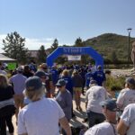 Colorado Walk & Roll participants gather at the start line and pass under the blue arch.