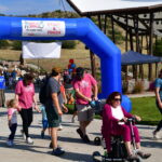 Colorado Walk participants walk and roll through the blue arch.